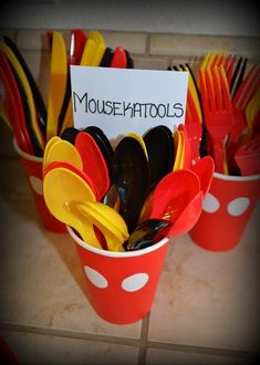 a cup filled with plastic utensils on top of a tiled counter next to a sign that says mousemattools