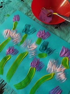 a child's hand is painting flowers on a piece of paper