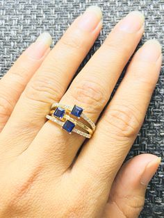 a woman's hand with two gold rings and blue stones on the ring finger