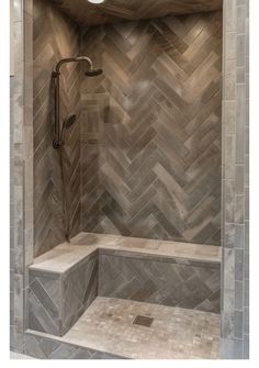 a walk in shower sitting next to a tiled wall and wooden floored area with light colored tiles on the walls