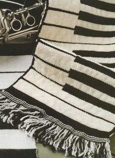 a black and white striped blanket sitting on top of a floor next to a bag