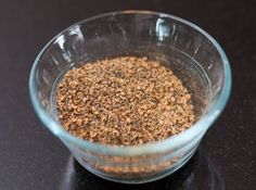 a glass bowl filled with spices sitting on top of a table next to a black counter