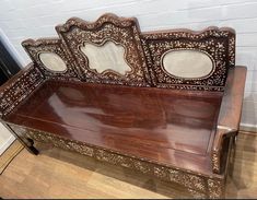 an ornate wooden bench sitting on top of a hard wood floor