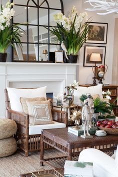 a living room filled with lots of furniture and flowers in vases on top of the fireplace