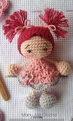 a crocheted doll is sitting on a blanket next to knitting needles and yarn