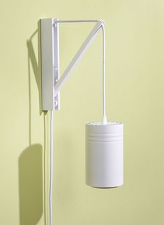 a white wall lamp on a yellow wall next to a light fixture with a plug in it