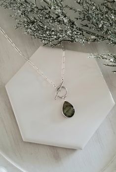 This modern chic necklace features a one of a kind completely natural Labradorite teardrop stone that hangs from a modern toggle clasp and joined to the very popular Paper Clip style chain. This necklace is available in two finishes...genuine Sterling Silver and !4k Gold Filled. These finishes are genuine metals, NOT plated and will never chip, peel or flake off.Necklace Details:* Raw Labradorite Teardrop Stone. Stone is faceted and bezel set. Size: 18 mm* Genuine Sterling Silver or Gold Filled Modern Teardrop Gemstone Necklace, Raw Labradorite, Paperclip Chain Necklace, Chic Necklace, Labradorite Necklace, Labradorite Necklaces, Modern Chic, Necklace Sterling Silver, Toggle Clasp