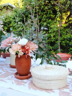 a table topped with vases filled with flowers and greenery on top of it