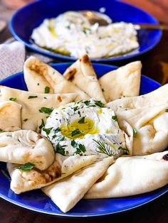 two plates with pita bread and hummus on them, one has an egg in the middle