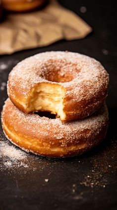 three doughnuts stacked on top of each other with powdered sugar around them