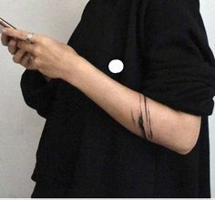 a woman holding a cell phone with her arm wrapped around the other hand and wearing a black shirt