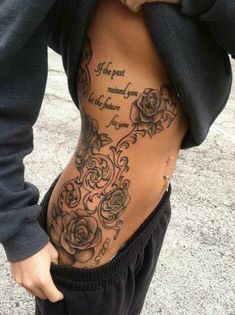 a woman's lower back tattoo with roses and words on the bottom part of her stomach