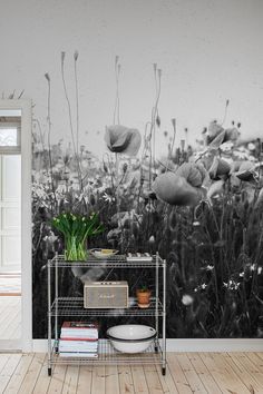 a black and white photo of some flowers on a shelf in front of a wall