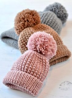 three knitted hats with pom - poms on them