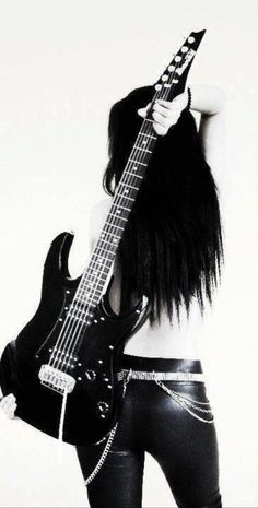 a woman with long black hair holding a guitar