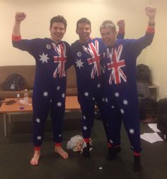 two men in union jack onesuits pose for the camera with their arms up