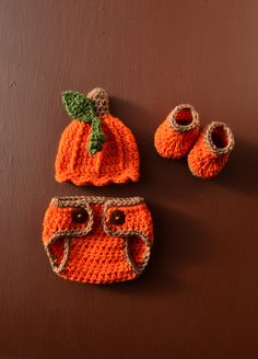 an orange crocheted hat, booties and diaper cover on a brown surface