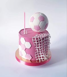 a pink and white cake with soccer balls on top, in the shape of a net