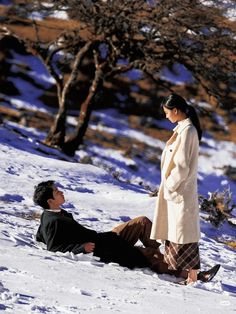 a man laying in the snow next to a woman