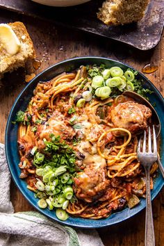 a blue plate topped with pasta and meat covered in sauce next to two slices of bread