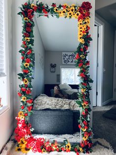 a mirror that has flowers on it in the middle of a room with a couch