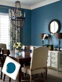 a dining room with blue walls and white furniture, chandelier above the table