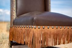 a brown leather chair with tassels and studding on the armrests