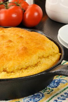 a skillet with cornbread and tomatoes in the background