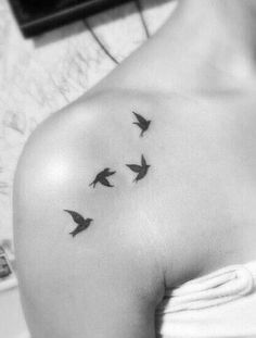 a woman's shoulder with three birds flying in the air on her left arm