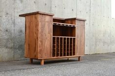 a wooden cabinet with wine racks in front of a concrete wall and cement flooring