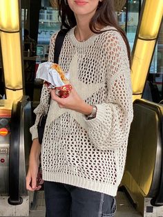 a woman standing in front of an escalator holding a piece of food and wearing a straw hat