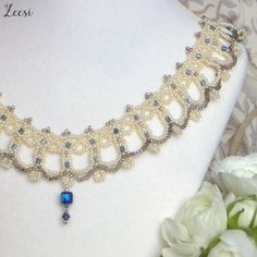 the necklace is adorned with pearls and blue glass bead accents on a mannequin