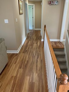 a hallway with hard wood flooring and white railings leading to the front door