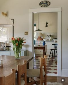 an open kitchen and dining room area with flowers in the vase on the wooden table