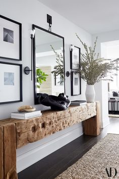 a wooden bench sitting in front of a mirror on top of a wall next to a potted plant