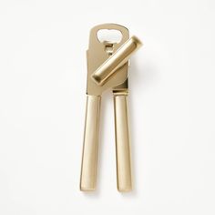 a gold colored bottle opener on a white surface with a key in the shape of a heart