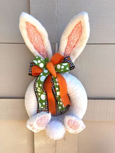 a stuffed bunny hanging on the side of a door with polka dot ribbon and bow