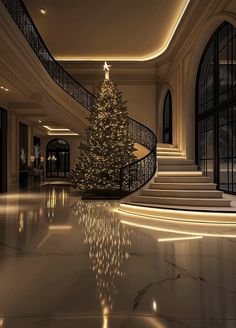 a lit christmas tree is in the middle of a large room with stairs and windows