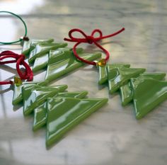 green christmas tree ornaments with red ribbon on marble counter top, ready to be used as ornament