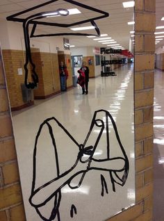 a mirror with a drawing on it in the middle of a hallway next to a brick wall