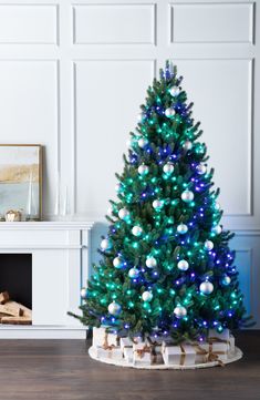 a blue and white christmas tree in a living room with wood burning place next to it