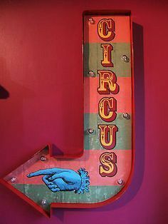 a neon sign that says circus on the side of a wall in front of a red wall