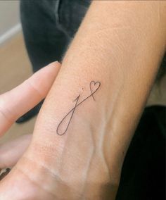 a woman's arm with a small tattoo on the wrist and a cross in the middle