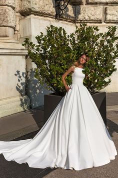 a woman in a white wedding dress standing next to a bush