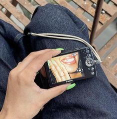 a woman holding her cell phone while sitting on a bench with green nail polishes