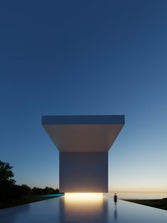 a person standing in front of a large white structure at dusk with the sun shining on it