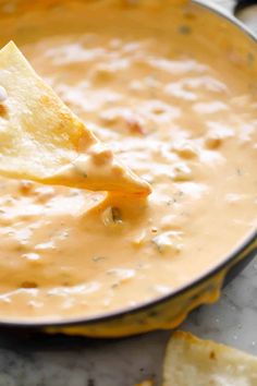 a tortilla chip being dipped with cheese