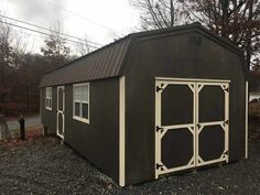 a black shed with white trim on the side and windows in the door is shown