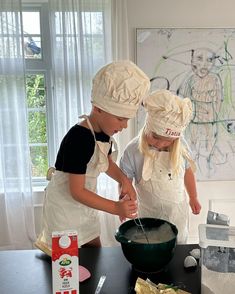 two children in chef's hats mixing batter into a bowl