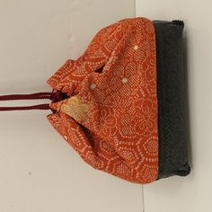 an orange and black bag hanging on the wall next to a white wall with a red string